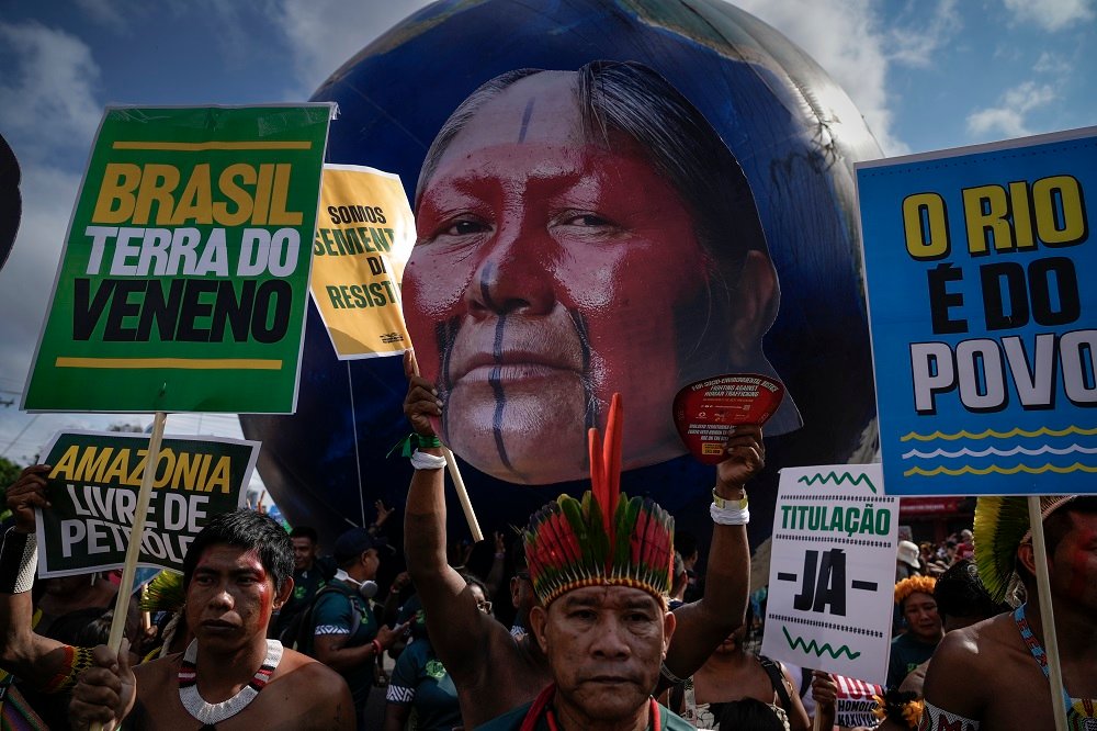 Kayapós carregam cartazes e foto da guerreira Tuíre Kayapó, durante a Marcha Mundial pelo Clima, em Belém, na COP30 (Foto: Fernando Martinho/Repórter Brasil)