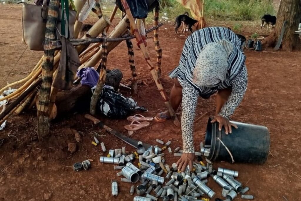 Anciã recolhe cápsulas de balas e recipientes de bombas de gás que foram disparadas pela Polícia Militar contra os Guarani-Kaiowá em 16 de outubro (Foto: Lídia Farias/Cimi/Divulgação)